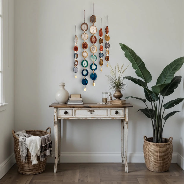 Decorative wall hanging above a wooden console table with plants and a basket in a room.