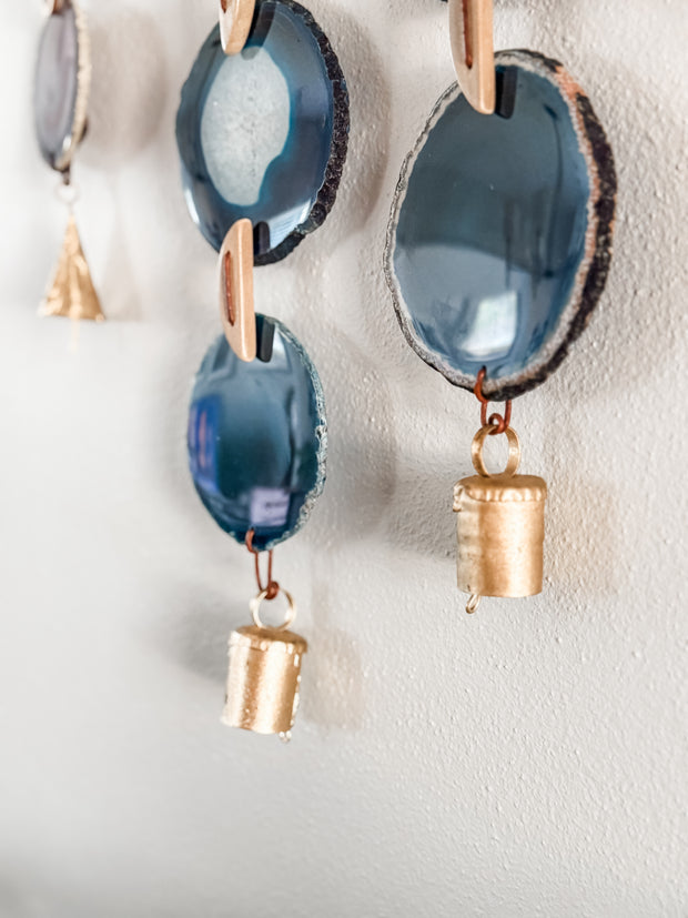 close up of agate slices with vintage brass bells on a white wall