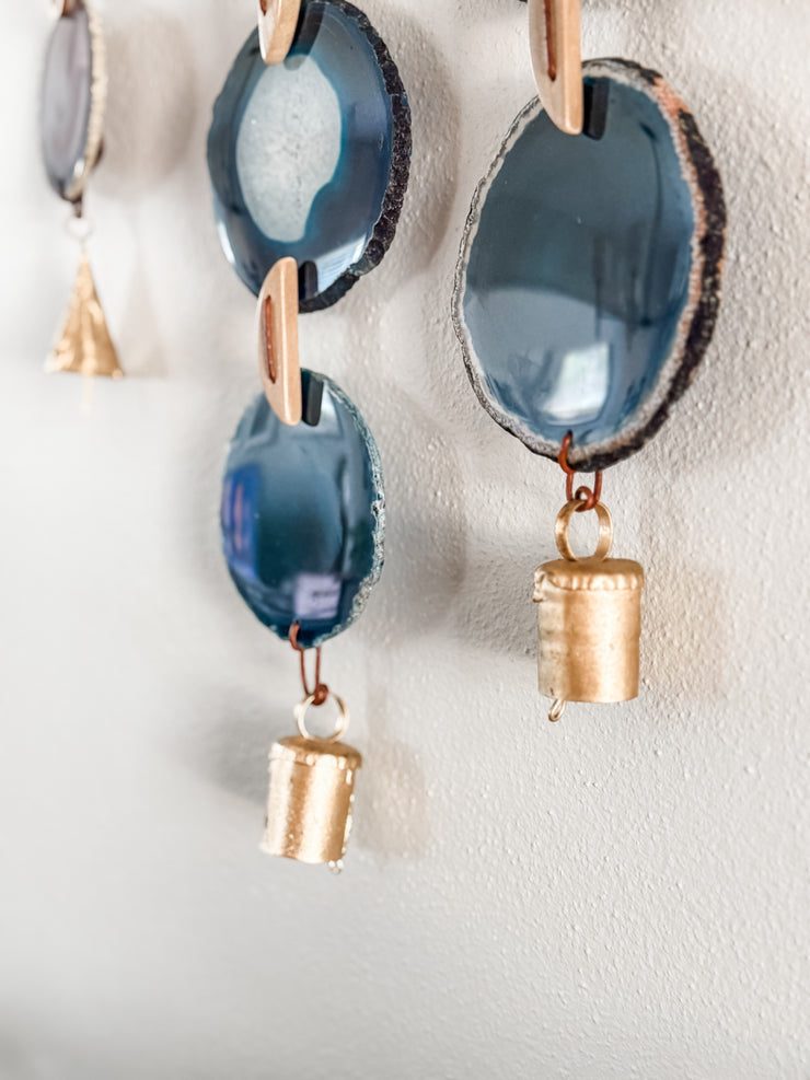 close up of agate slices with vintage brass bells on a white wall