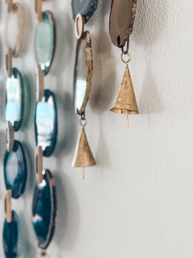 close up of agate slices with vintage brass bells on a white wall