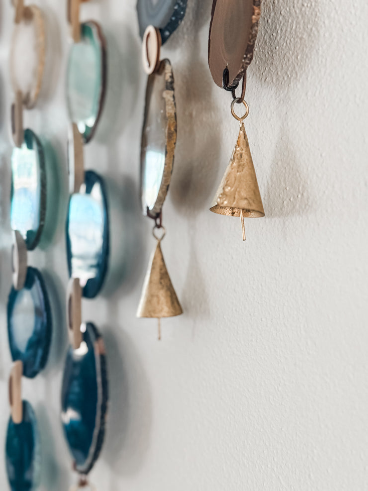 close up of agate slices with vintage brass bells on a white wall
