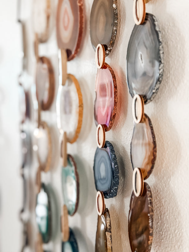 Decorative wall art with circular agate slices in various colors on a textured white background