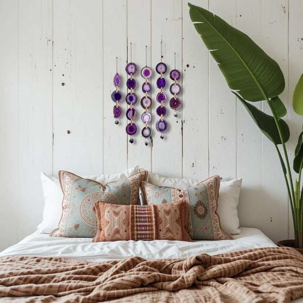 Decorative pillows on a bed with a wall hanging and plant in the background