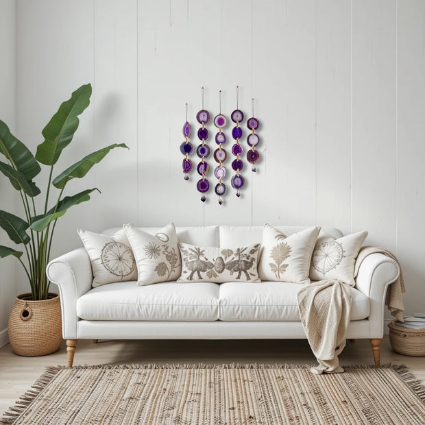 White sofa with decorative pillows and a plant in a room with a wall hanging.