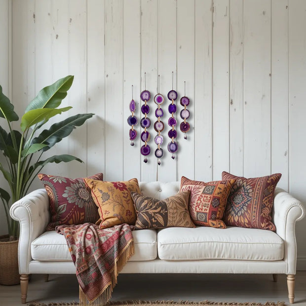 White sofa with patterned cushions and a colorful blanket against a wooden wall with decorative elements.