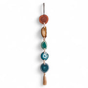 Decorative wall hanging with turquoise stones and wooden elements on a white background