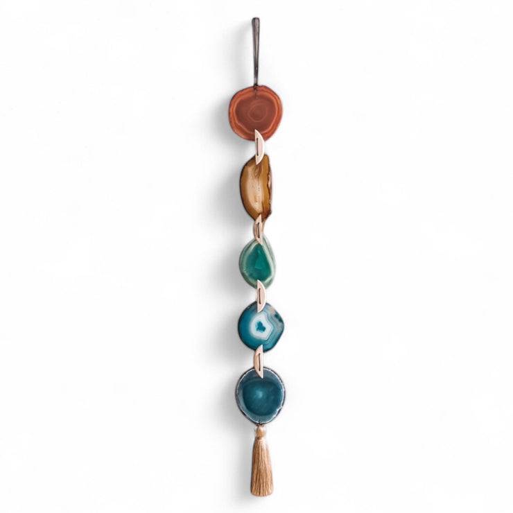 Decorative wall hanging with turquoise stones and wooden elements on a white background