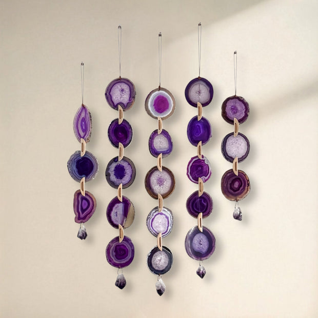 Set of purple agate slices hanging against a beige background