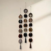 Decorative hanging mobile with circular and teardrop shapes on a plain background