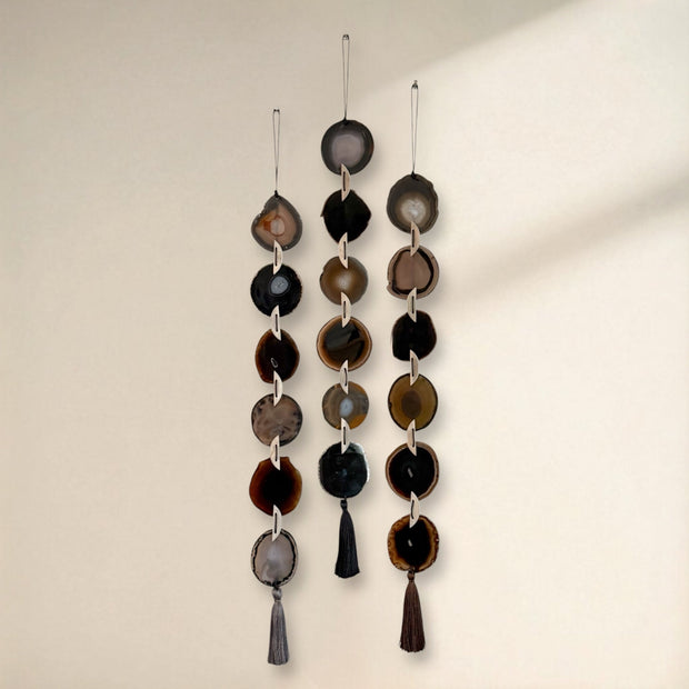 Decorative hanging mobile with circular and teardrop shapes on a plain background