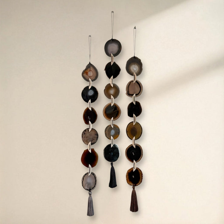 Decorative hanging mobile with circular and teardrop shapes on a plain background